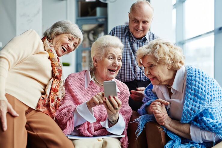 A group of four older adults using a smartphone