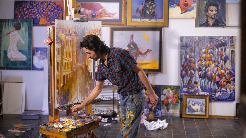 Professional male artist paints with oil on canvas in studio